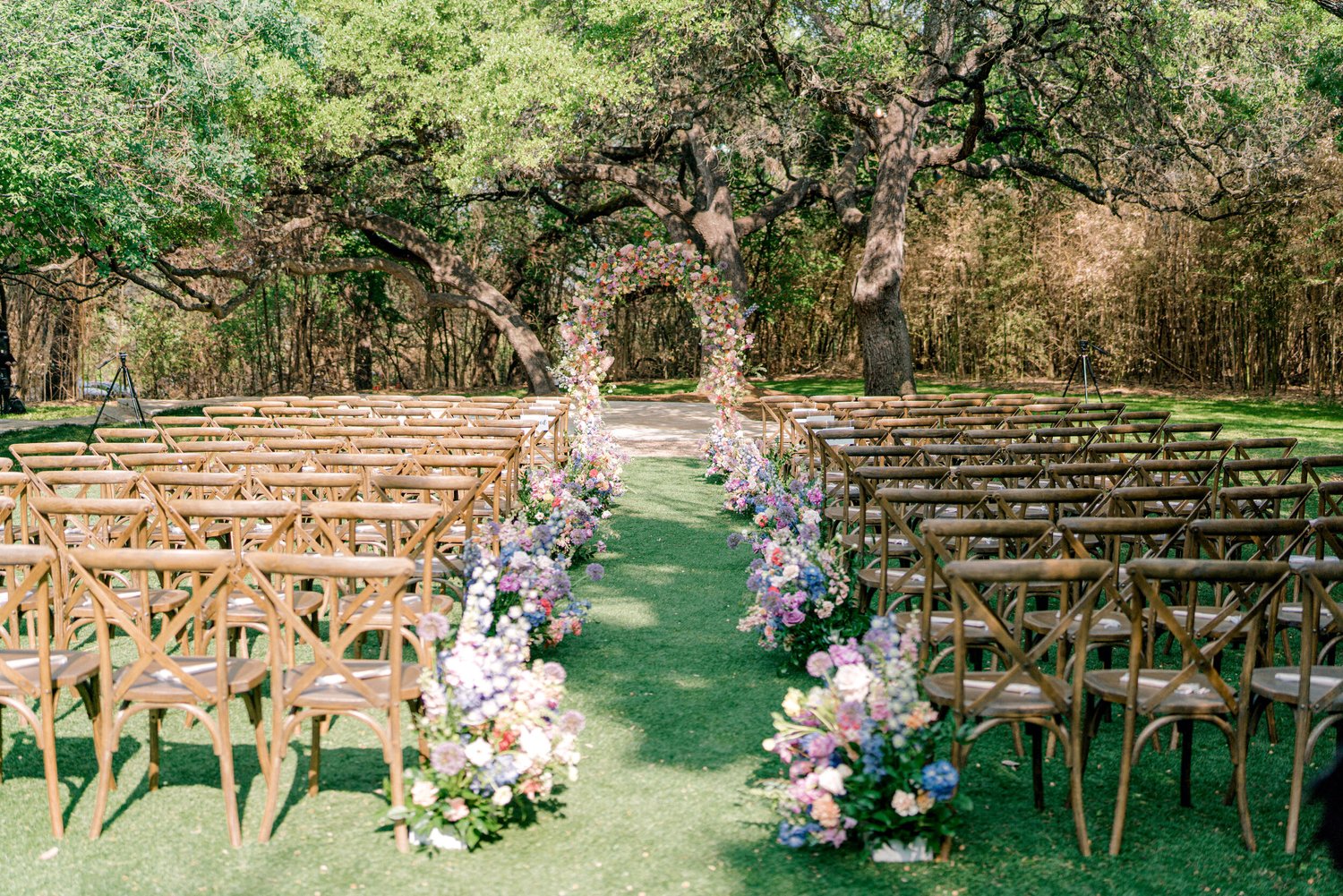Outdoor ceremony aisle and floral arch under the oaks