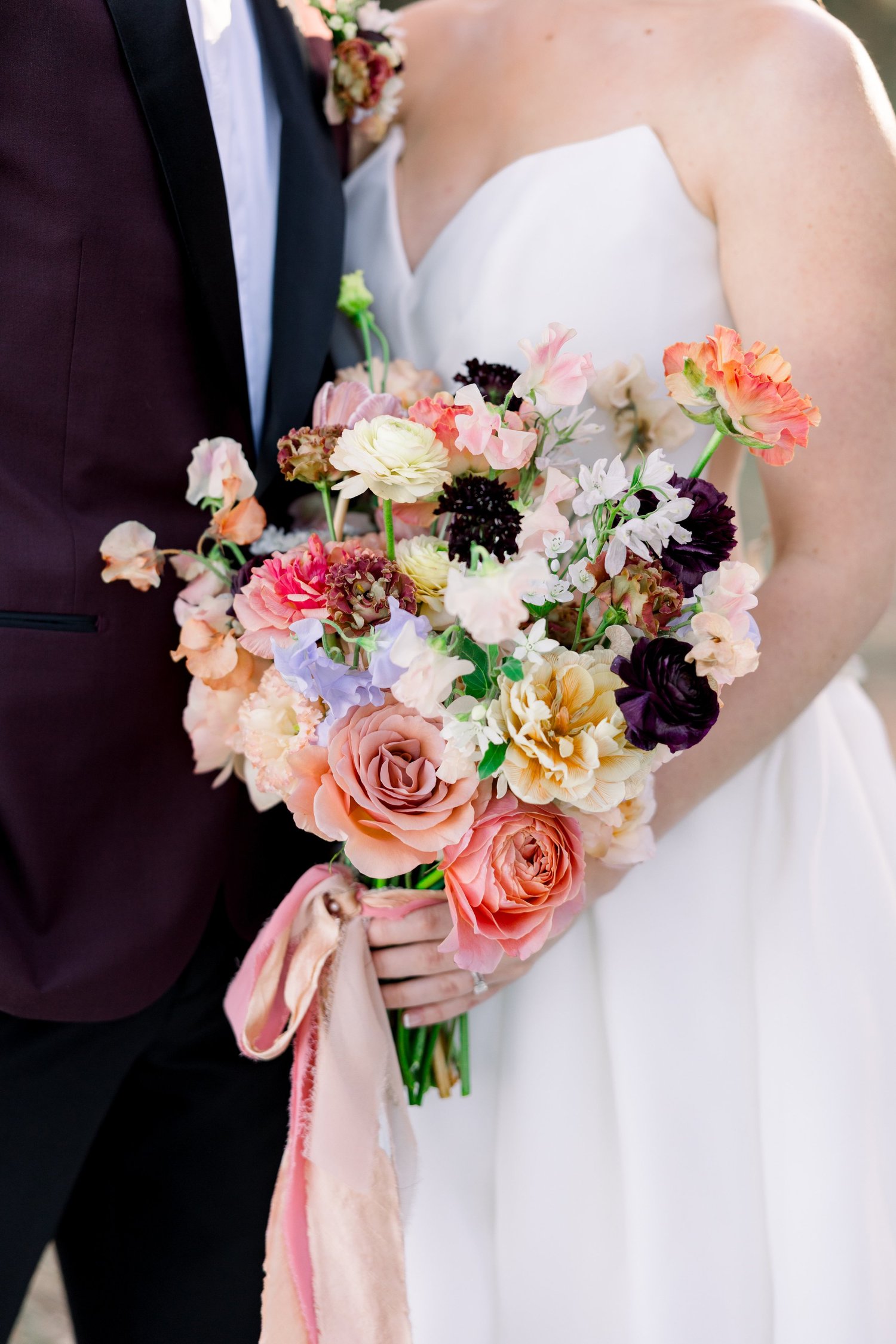 Bride with a lush, color-filled bridal bouquet beside the groom