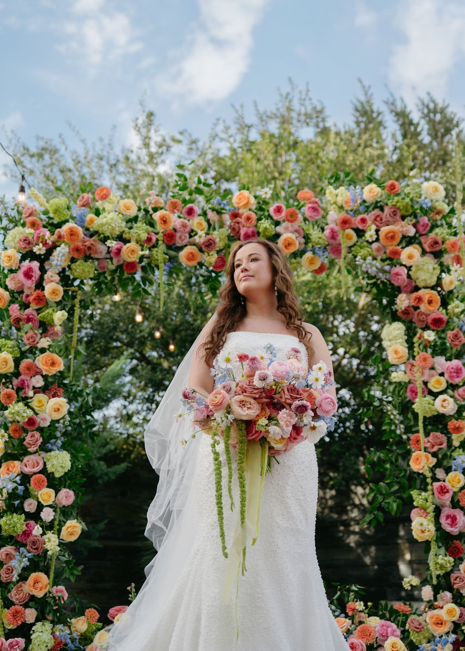 Bride before a vivid garden-flower ceremony arch